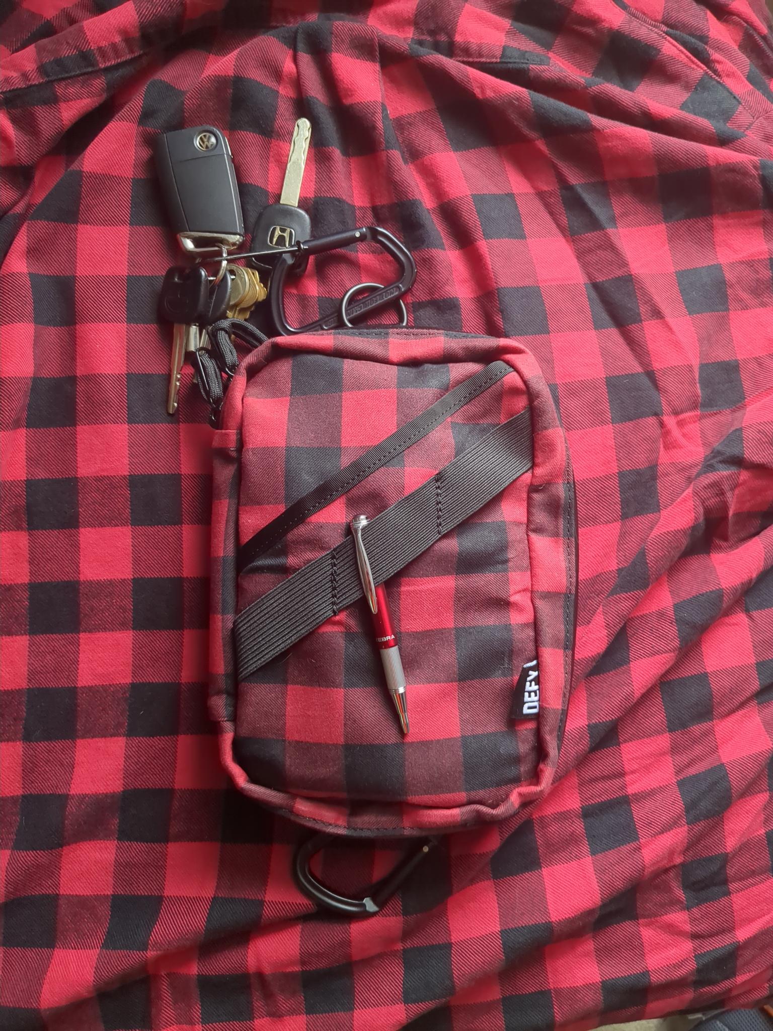 DEFY Bags Void pouch in buffalo plaid laying on a buffalo plaid shirt