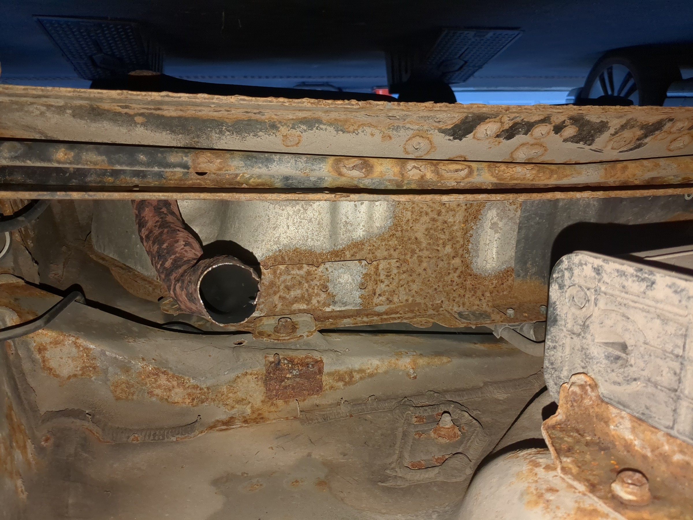 Rusty underside of a 2005 Scion xB with a muffler missing